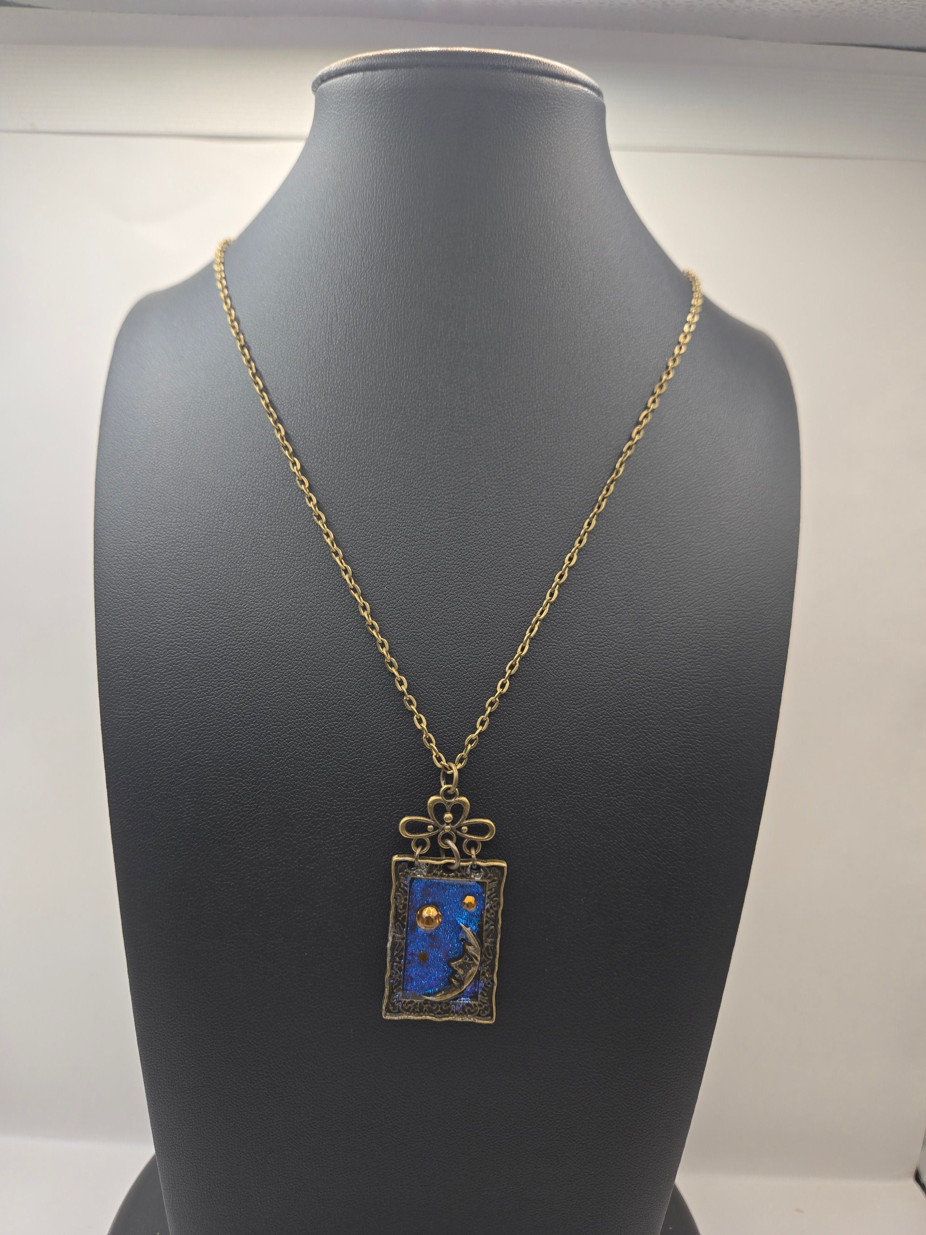 Necklace with a blue pendant on a mannequin bust against a neutral background